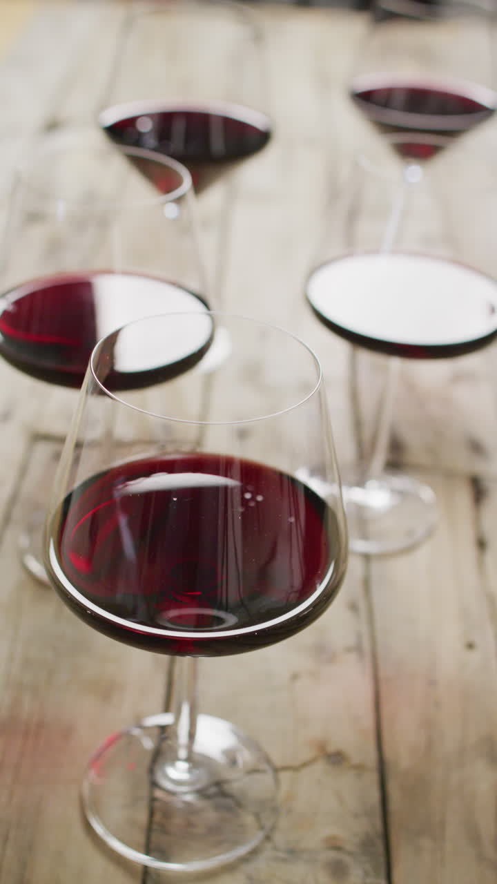 Eleganti bicchieri da vino pieni di vino rosso sono disposti su un tavolo di legno