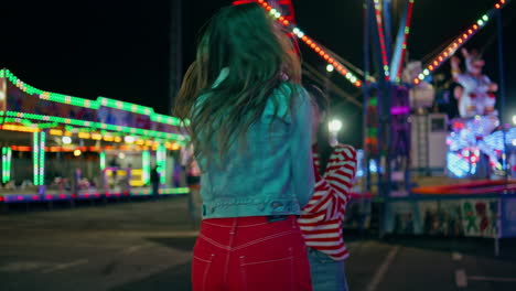 smiling girl hitting boxing machine at amusement park. cheerful teenagers fun