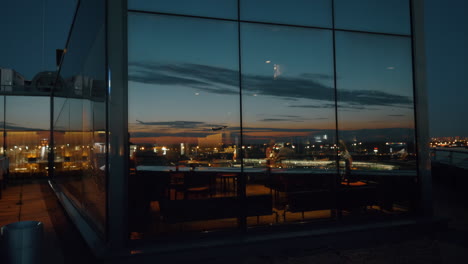 City-at-night-and-plane-taking-off-in-window-reflection