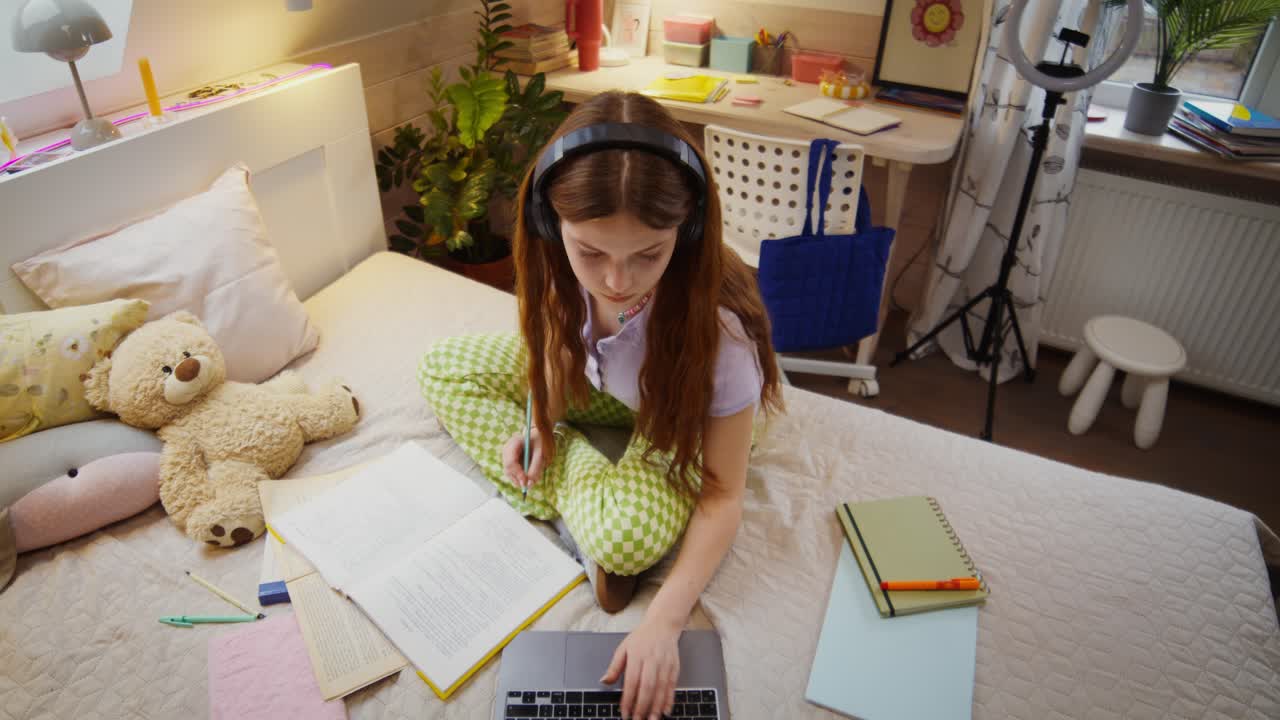 подростковая девушка учится на кровати с ноутбуком