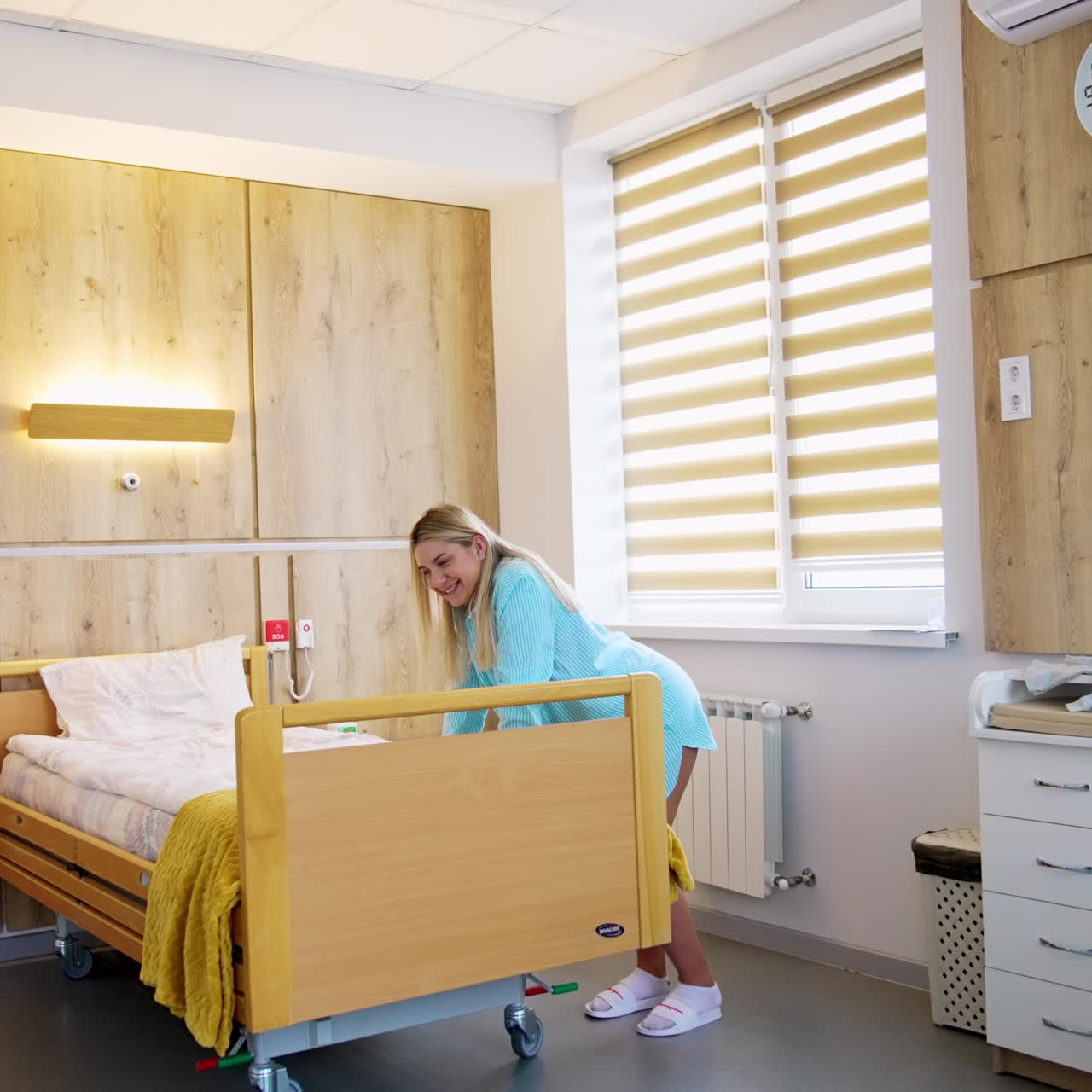Pregnant woman stands leaned over bed in a maternity hospital ward. Preparation for a baby delivery
