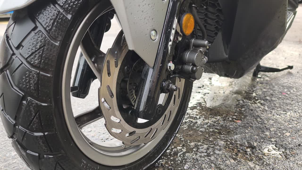 Close-up of a scooter's disk brake system, featuring ABS and TCS technology. This system is crucial for safety when navigating wet and slippery roads