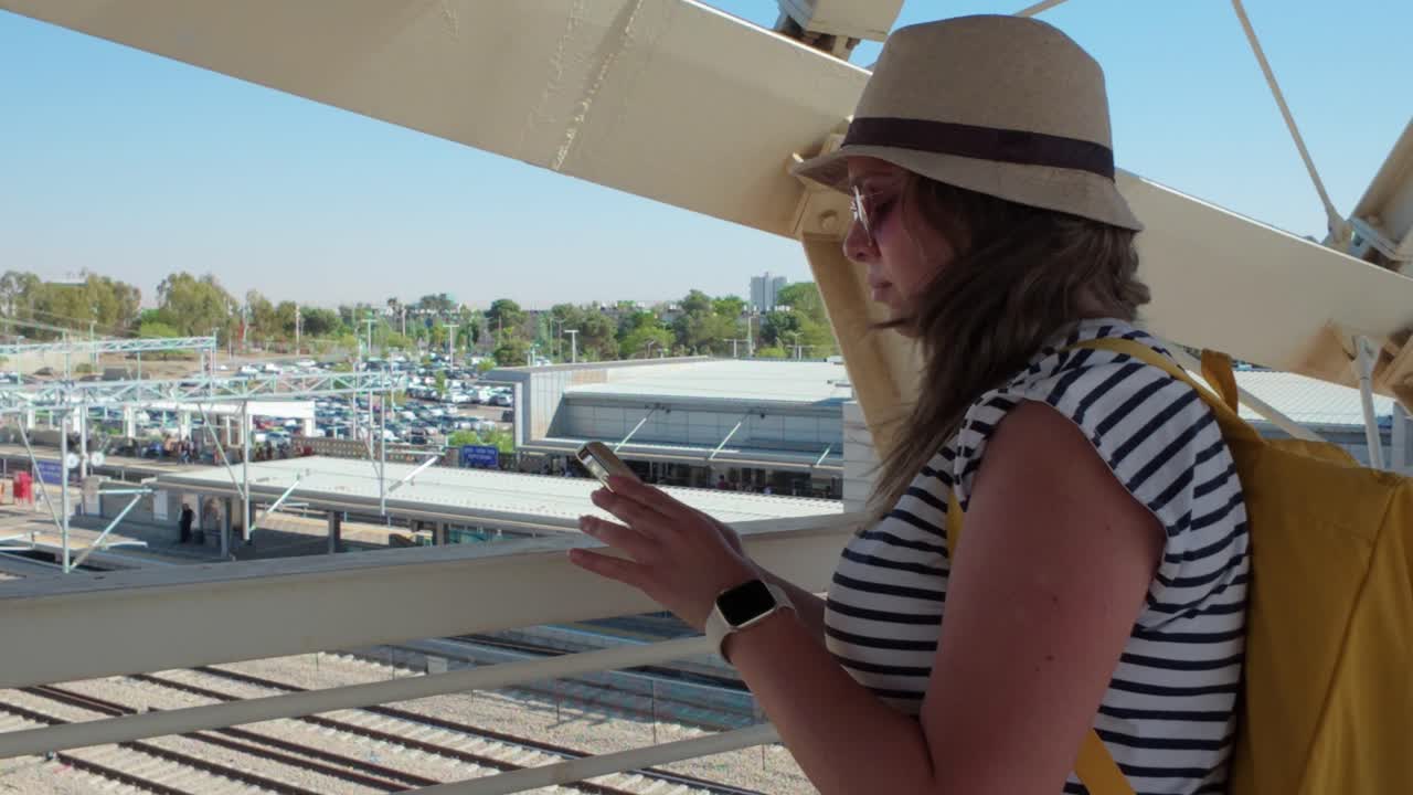 Tourist checks her messages while waiting on a bridge