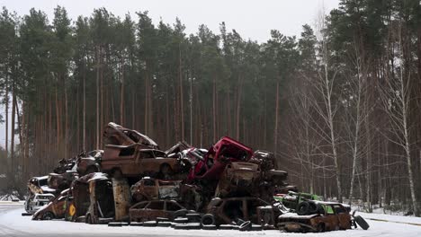 a snowy winter scene shows a pile of charred and destroyed cars, stacked in irpin, ukraine, after intense battles between ukrainian and russian forces in the ongoing conflict.
