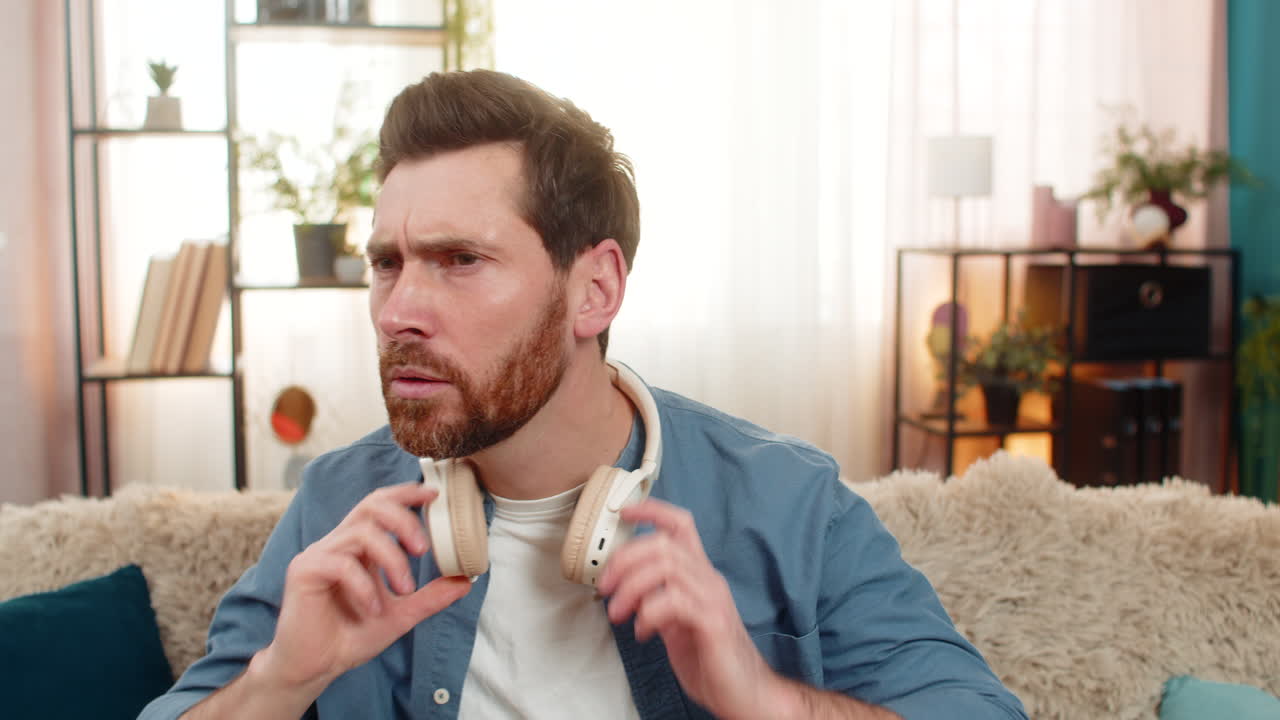 Man in headphones suddenly takes them off looking surprised reacting to strange unexpected sound