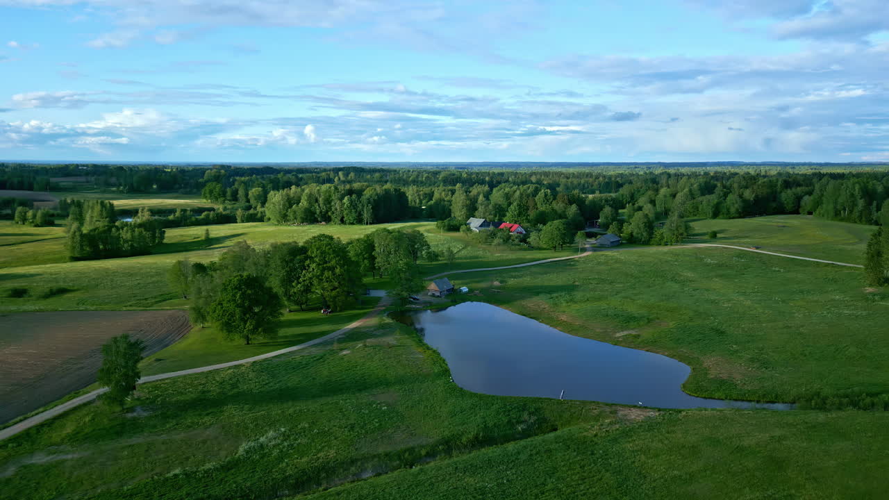 Droonikuva ilmasta maalaistilasta, jossa on lampi ja kaunis taivas.