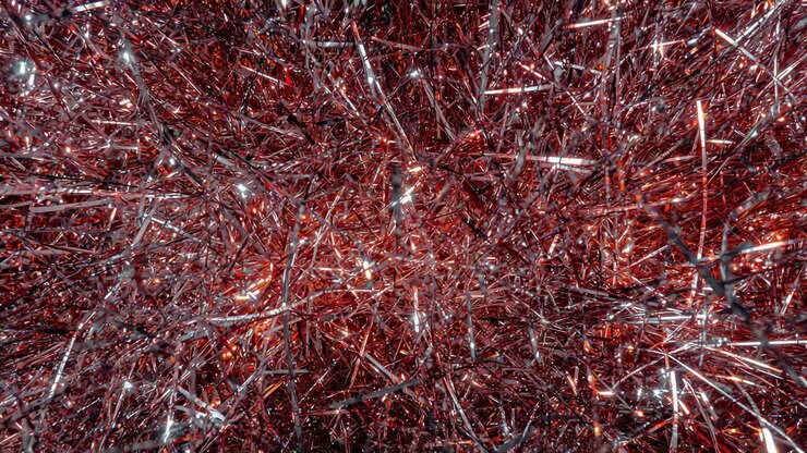 Sparkling red-silver tinsel shifting in studio close-up as gentle camera move, making glints