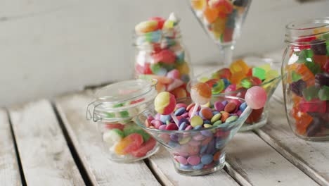 video of colourful various sweets in glass vessels on wooden table