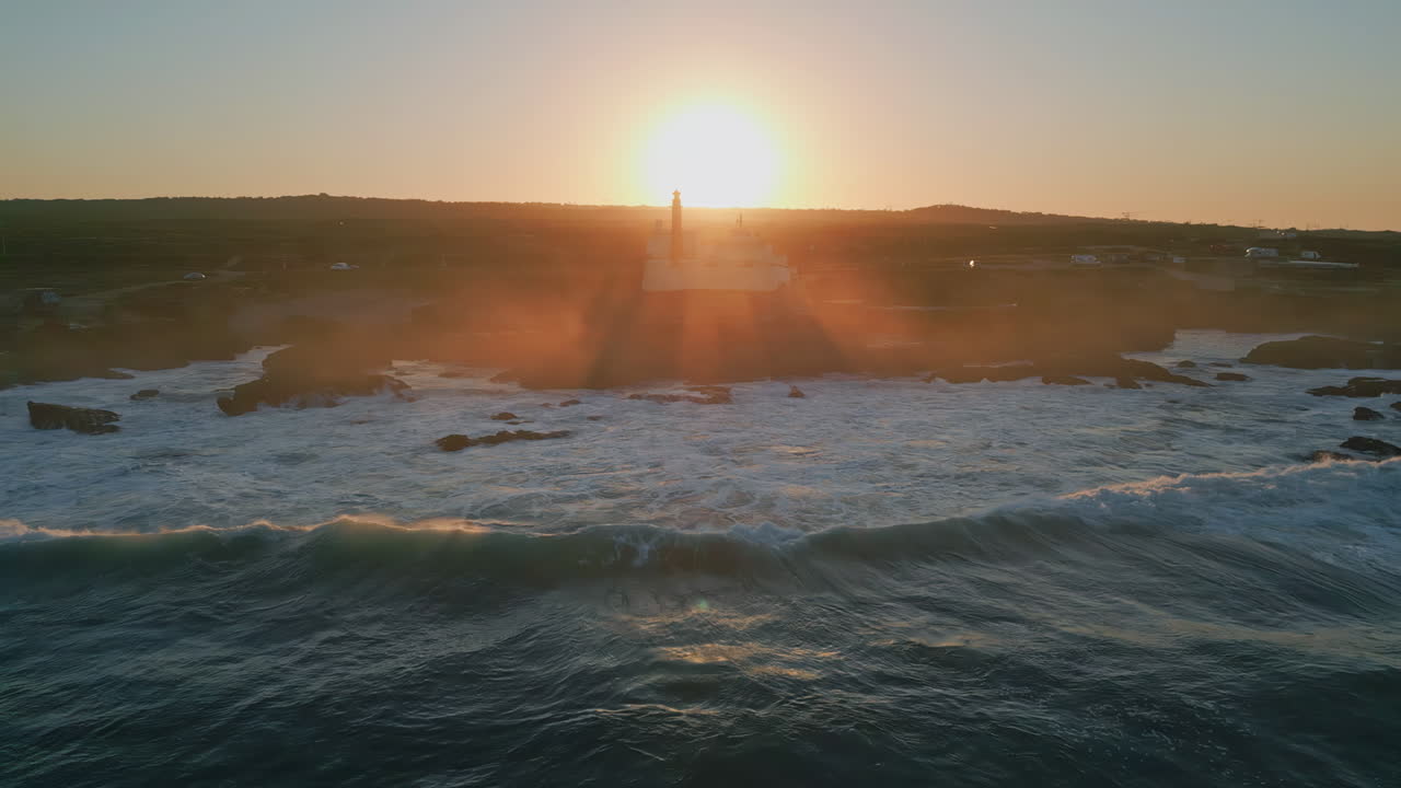 Silhouette lighthouse summer sunset drone view. Foamy ocean water splashing