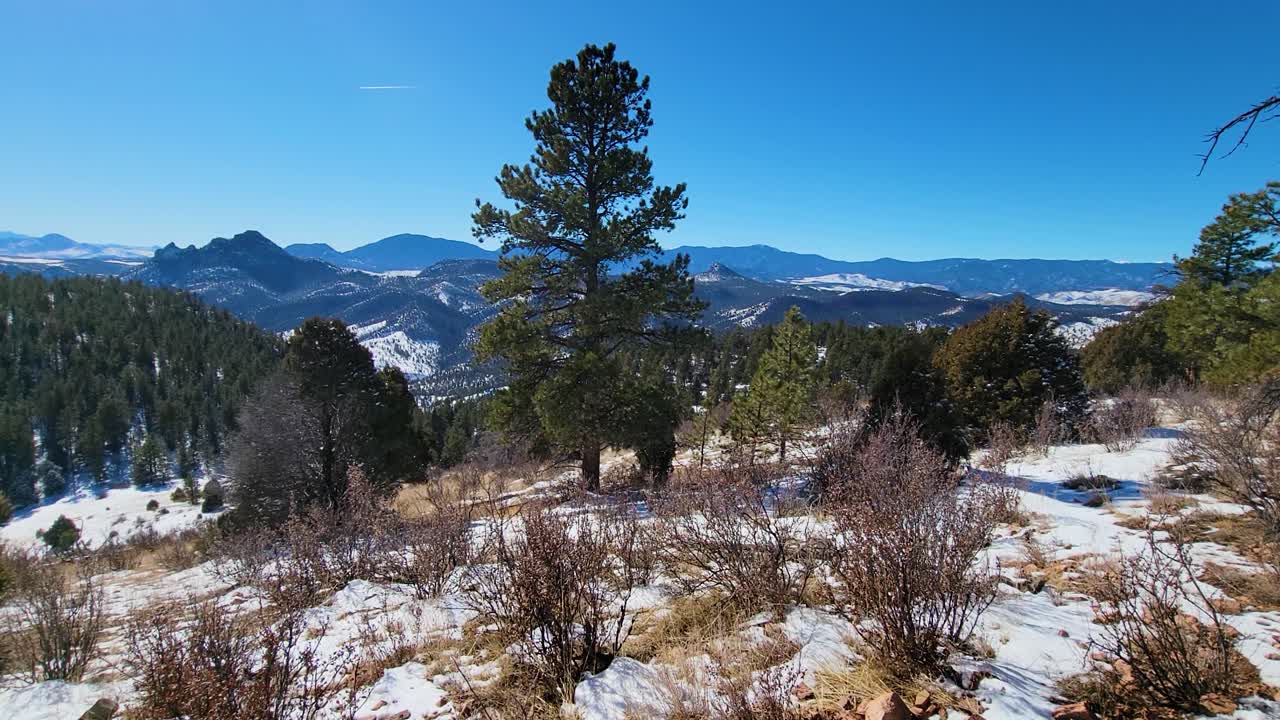 vista de caminatas invernales a través de las montañas rocosas cubiertas de nieve y el bosque de pinos.