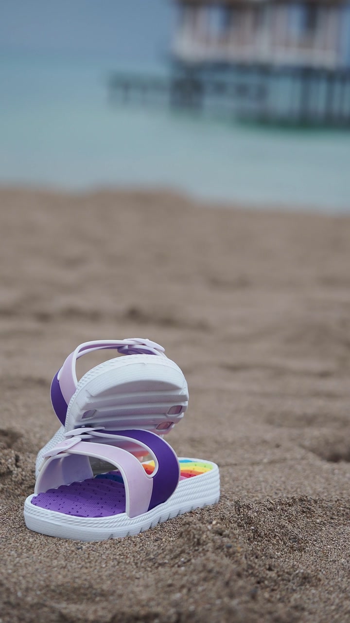 Vibrant Sandals on a Beach with a Blurred Ocean View