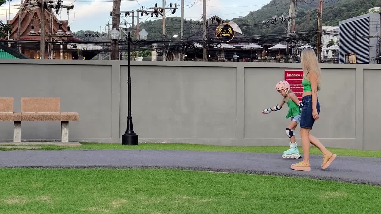 어머니 와 딸 이 공원 에서 롤러 스케이팅 을 하고 있다