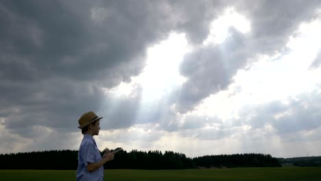 boy uses a tablet on a background of beautiful clouds, looks at the sky