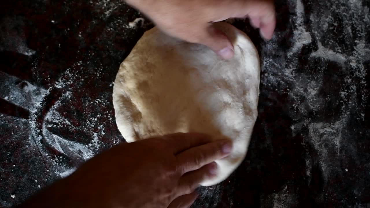 Working on a home made pizza dough on a marble kitchen counter. High angle shot. Side lit by natural window light