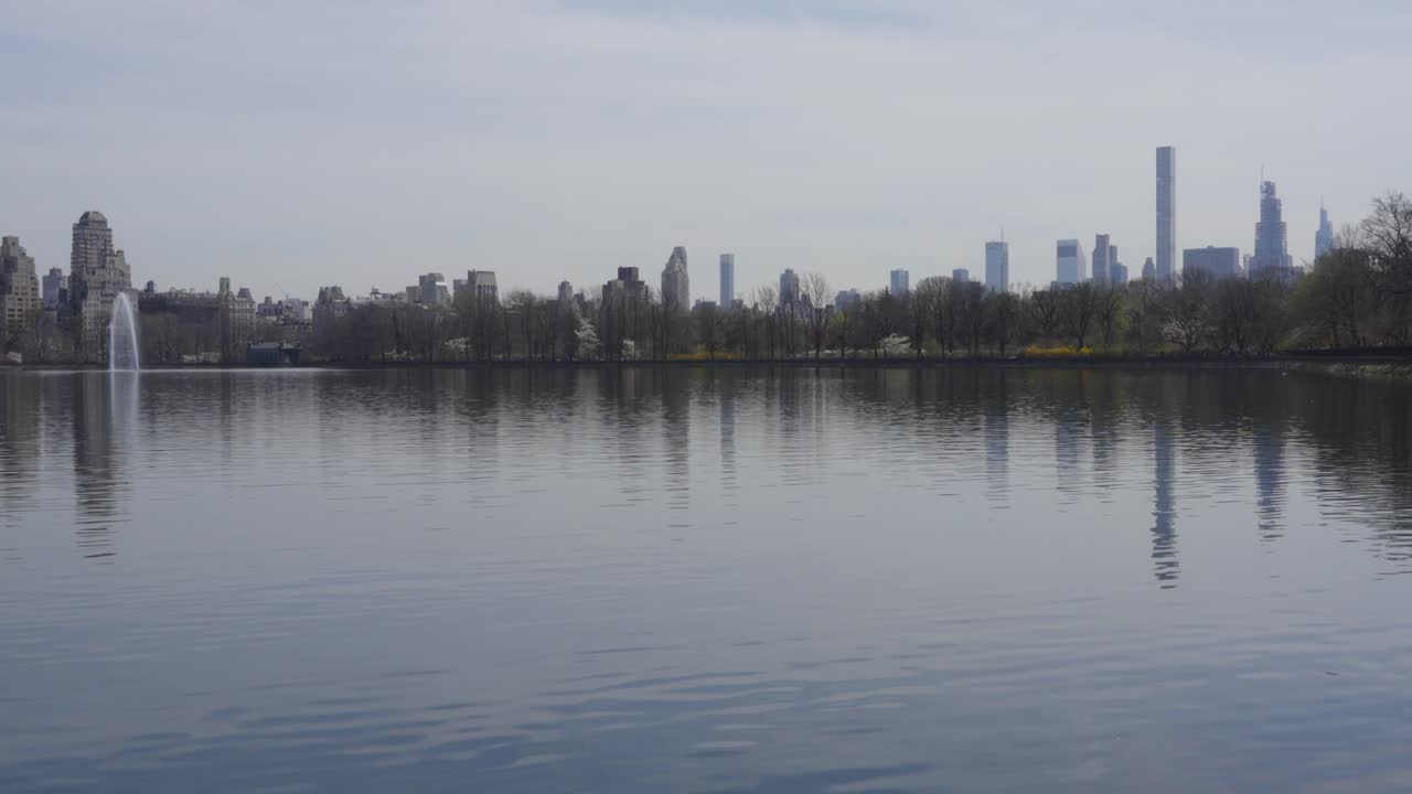 센트럴 파크 저수지의 조용한 물에 반사된 뉴욕 시의 평온한 전망은 바쁜 도시 속에서 평온의 본질을 포착합니다.