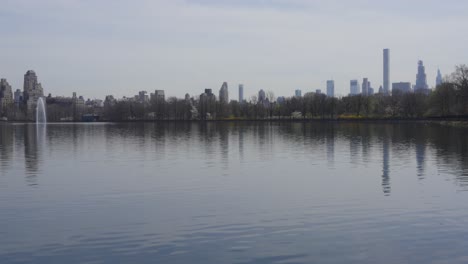 a peaceful view of new york city's skyline reflected on the calm waters of central park's reservoir, capturing the essence of tranquility amidst the bustling city