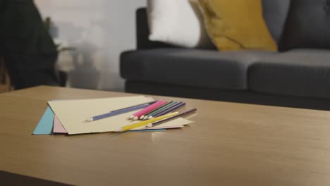 persona que ordena lápices de color y papel en la mesa en casa para un niño diagnosticado con tea