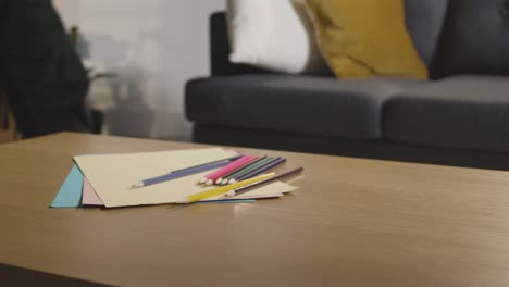 person tidying coloured pencils and paper on table at home for child diagnosed with asd