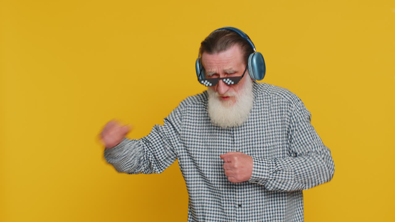 Äldre stilig gammal man lyssnar på musik via hörlurar och dansar glad farfar pensionär