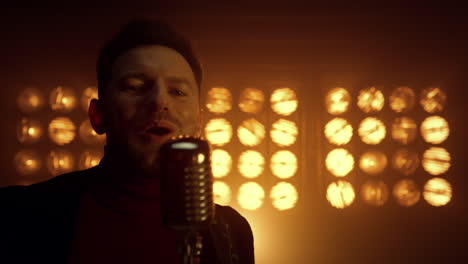 hombre guapo cantando en el micrófono en el escenario de cerca. vocalista actuando en un club nocturno.