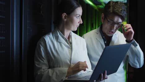 diversas mujeres y hombres técnicos de ti en batas de laboratorio usando computadoras portátiles comprobando el servidor de la computadora