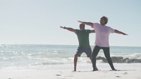 Glückliches-älteres-Afroamerikanisches-Paar,-Das-Yoga-Macht-Und-Sich-Am-Strand-Dehnt,-In-Zeitlupe