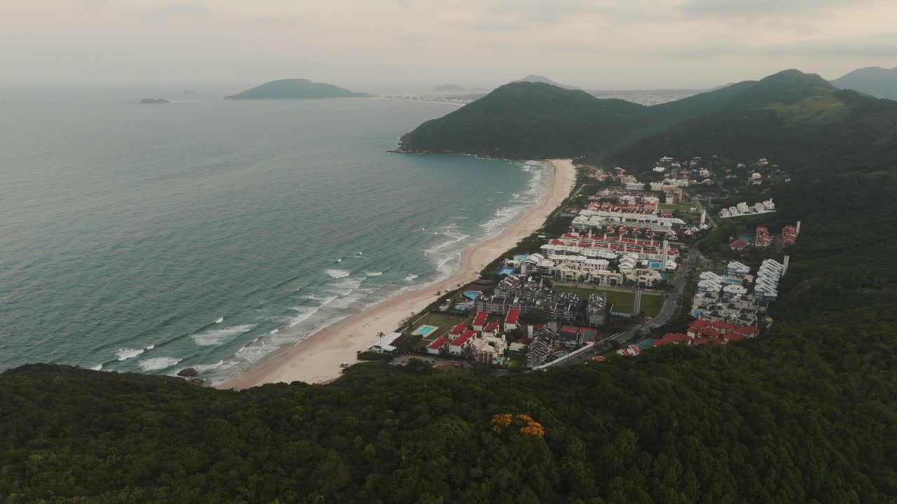 vista aérea que revela la playa de brava en florianópolis durante una puesta de sol nublada
