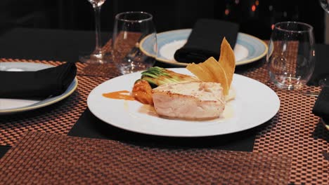 plate of halibut with garlic sauce on the table with crystal glasses of wine in a fancy restaurant