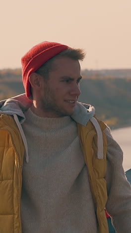 guy gets out of blue tent and stretches arms against calm river in early autumn morning closeup slow motion