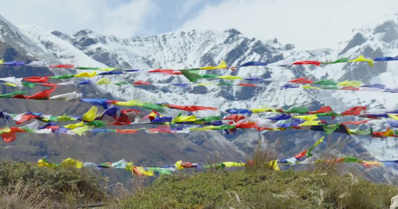 Elokuvamainen staattinen kuva vangitsee eloisia buddhalaisia rukouslippuja, jotka liehuvat kauniisti kylmässä tuulessa sumuisten valkoisten pilvien taustaa vasten Mustangissa, Nepalissa.