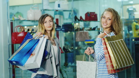 dos amigos se divierten bailando con bolsas de compras en el fondo de vitrinas de vidrio en la tienda