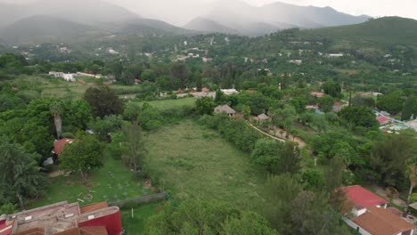 dynamic aerial of a town surrounded by tropical rainforest in the rain