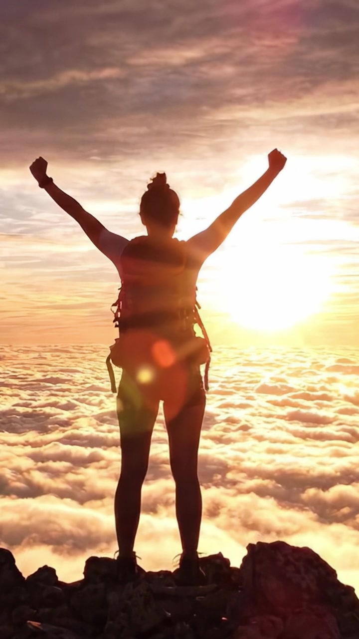 Escursionista trionfante che celebra all'alba sulla cima di una montagna sopra le nuvole, abbracciando la bellezza della natura e lo spirito d'avventura in un paesaggio mozzafiato