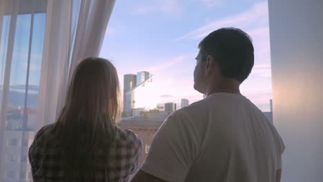 young couple looking at big city through the window