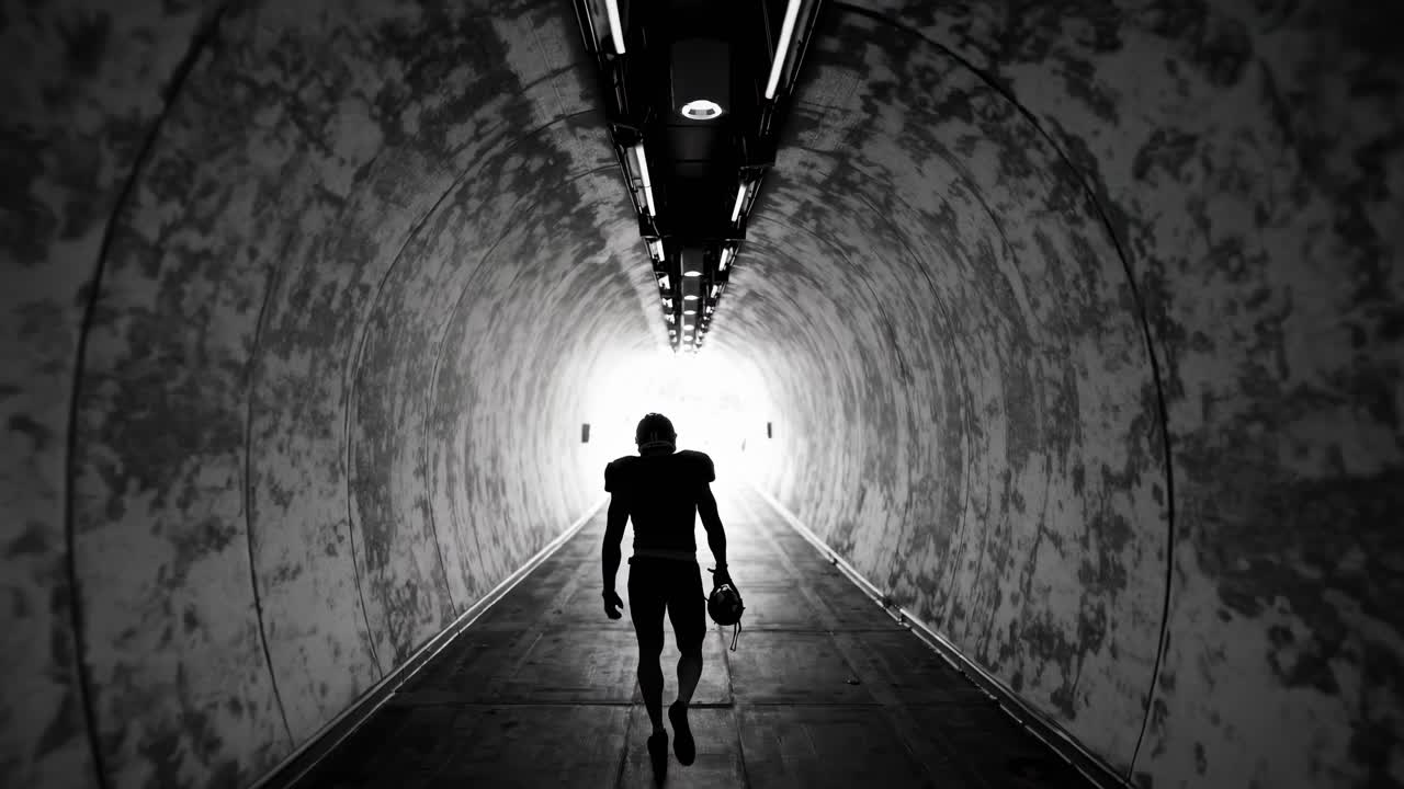 Silhouette of a football player walking through a tunnel, captured from a low angle