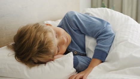 close-up view of cute small blond boy sleeping on the bed in the morning