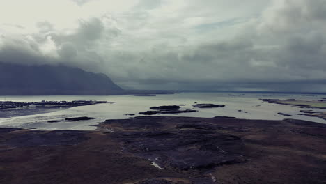 Drone-flight-over-town-surrounded-by-water-and-mountains