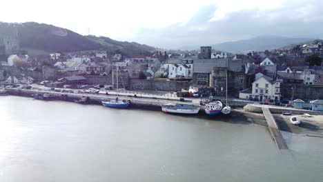 idyllic conwy castle and harbour fishing old town boats on coastal waterfront aerial left dolly