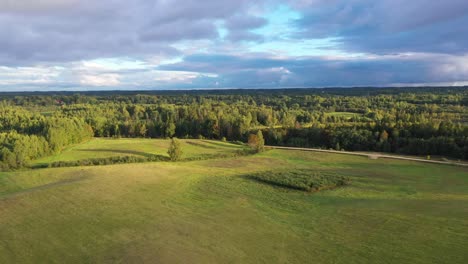 lush green fields and trees with calm lake behind at golden hour sunset in strante, latvia