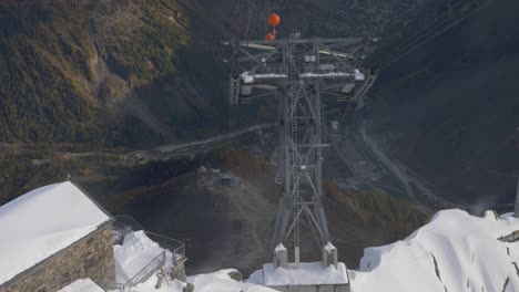 slow-motion-view-of-from-sky-lift-cabin-going-down,-construction,-city-and-mountains-in-background