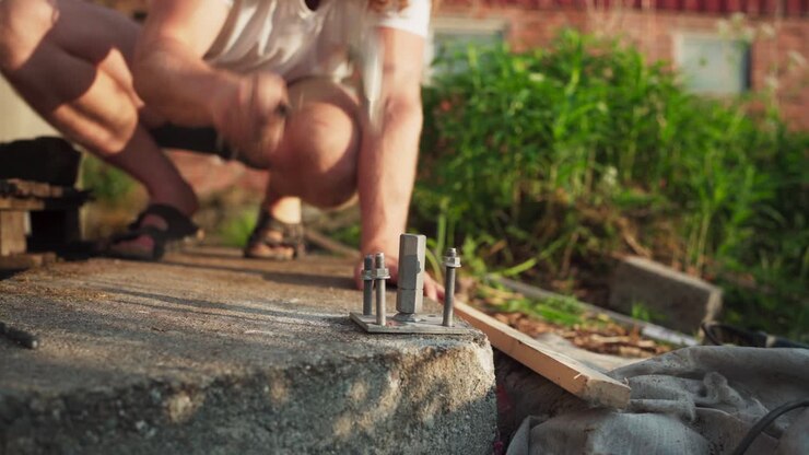 Worker Hammering Concrete Anchor Bolts Outdoor, Joining Metal Base Plate To Pedestal