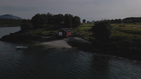 wooden boat dock on the shore with small boathouse in countryside of nordland, norway. - aerial