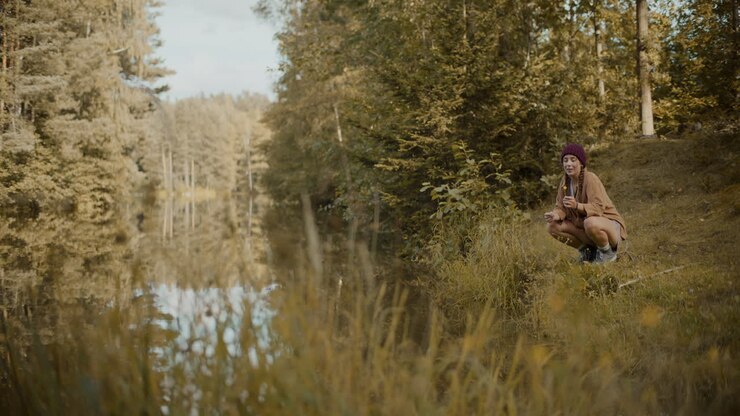 женщина-турист, держащая цветок, в то время как присев на траве