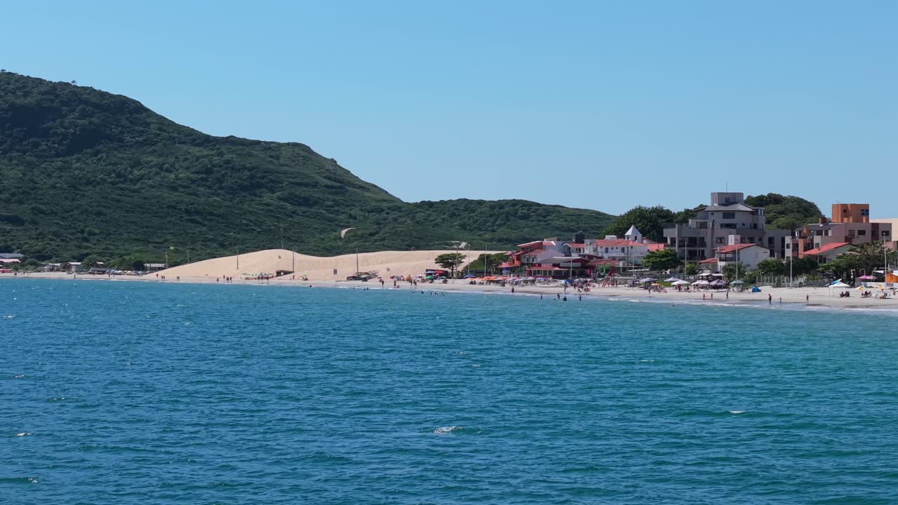 Costa di Praia dos Ingleses con acqua oceanica, spiaggia sabbiosa, dune e edifici sul mare a Santa Catarina, Brasile, sfondo aereo teleobiettivo.