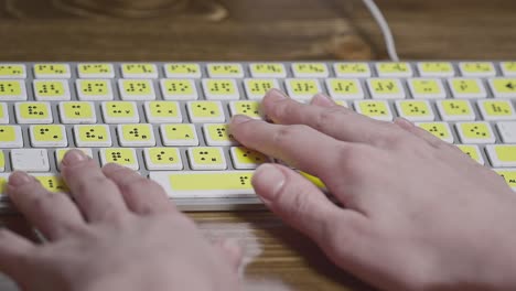 close-up of a computer keyboard with braille. a blind girl is typing words on the buttons with her hands. technological device for visually impaired people.