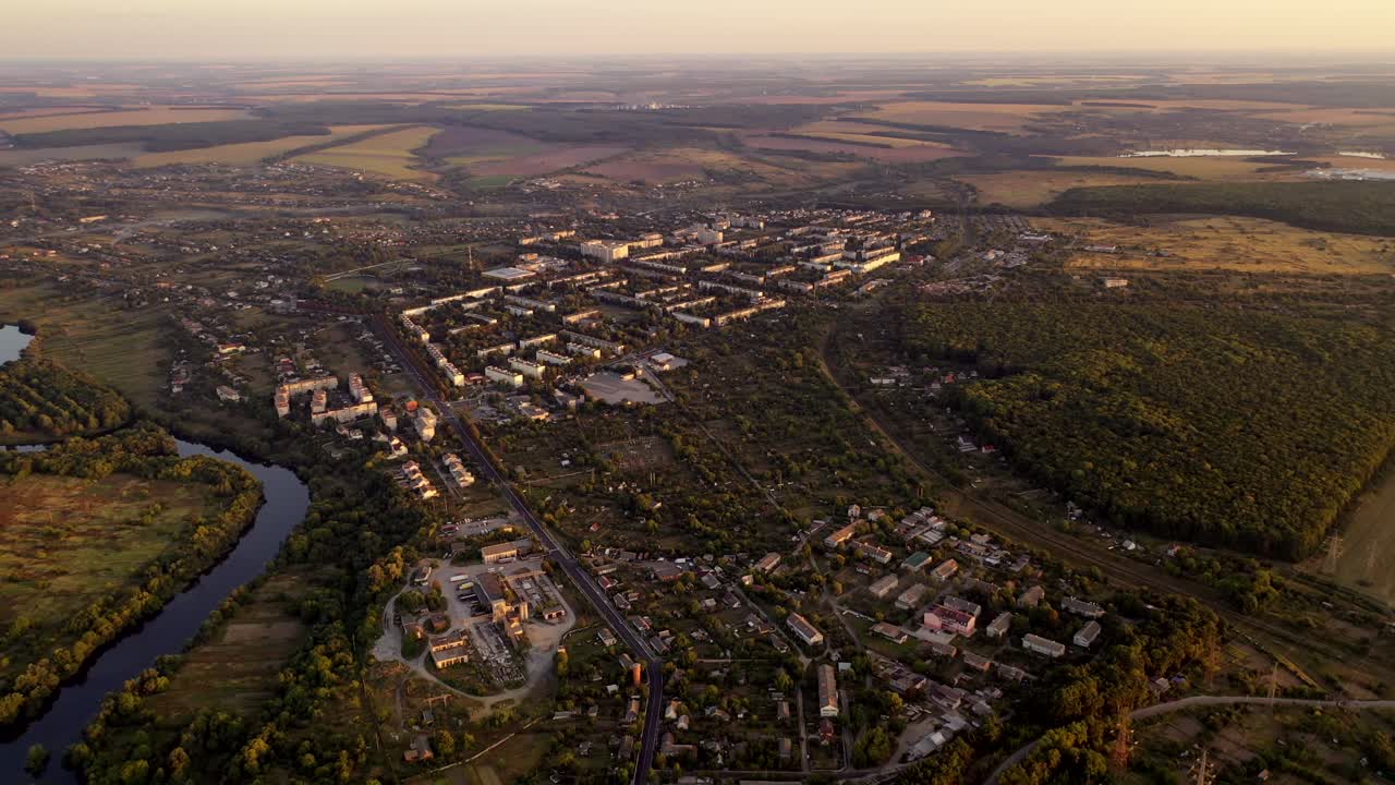 Aerial footage over small town in nature. Flight over the small buildings among fields in summer. Aerial view.