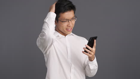 asian man using smartphone and getting frustrated.