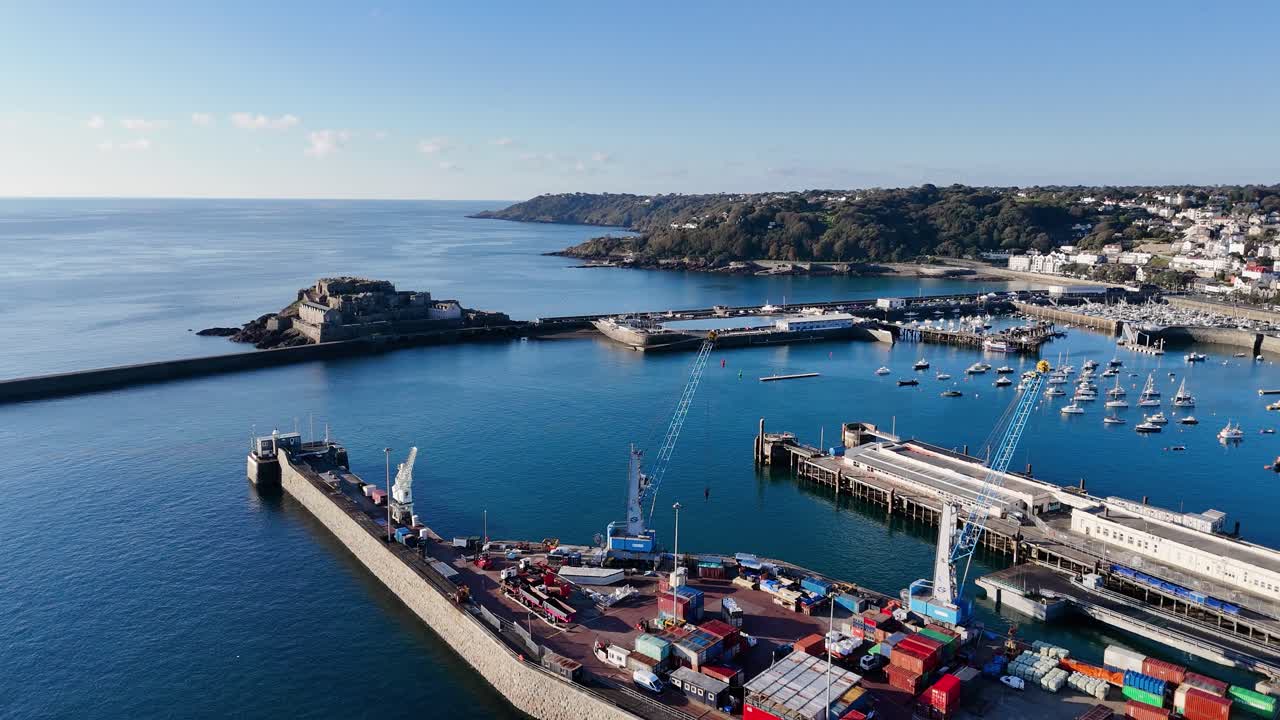 Immagini aeree riprese da drone di St Peter Port, Guernsey, che mostrano l'attracco dei traghetti, i moli, il Castello Cornet e il porto con vista su St Martin, con uno splendido mare calmo e blu intenso al sole del tardo pomeriggio