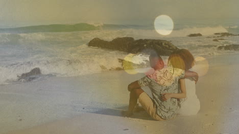 on sandy beach, couple watching colorful light animation with ocean waves nearby