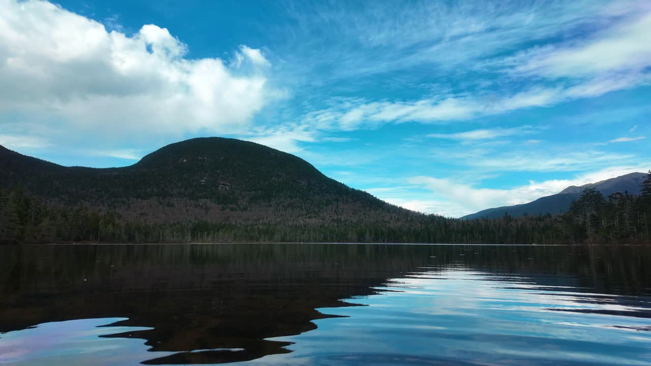 Still lake view reflects mountain and clouds in vibrant light, New Hampshire setting